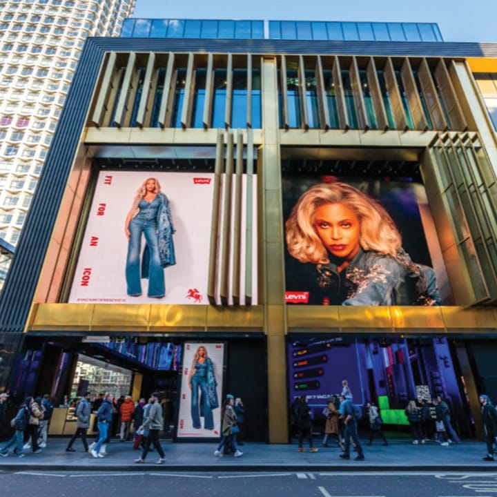 Storefront with people walking outside with digital ads on the store.
