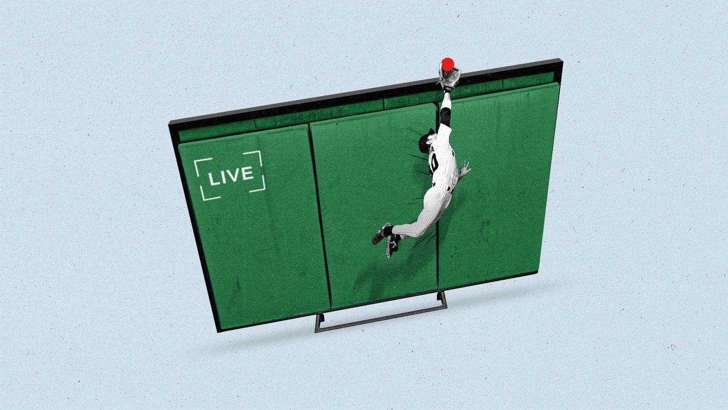 A baseball player jumps to catch a ball over a tv screen that looks like a field.