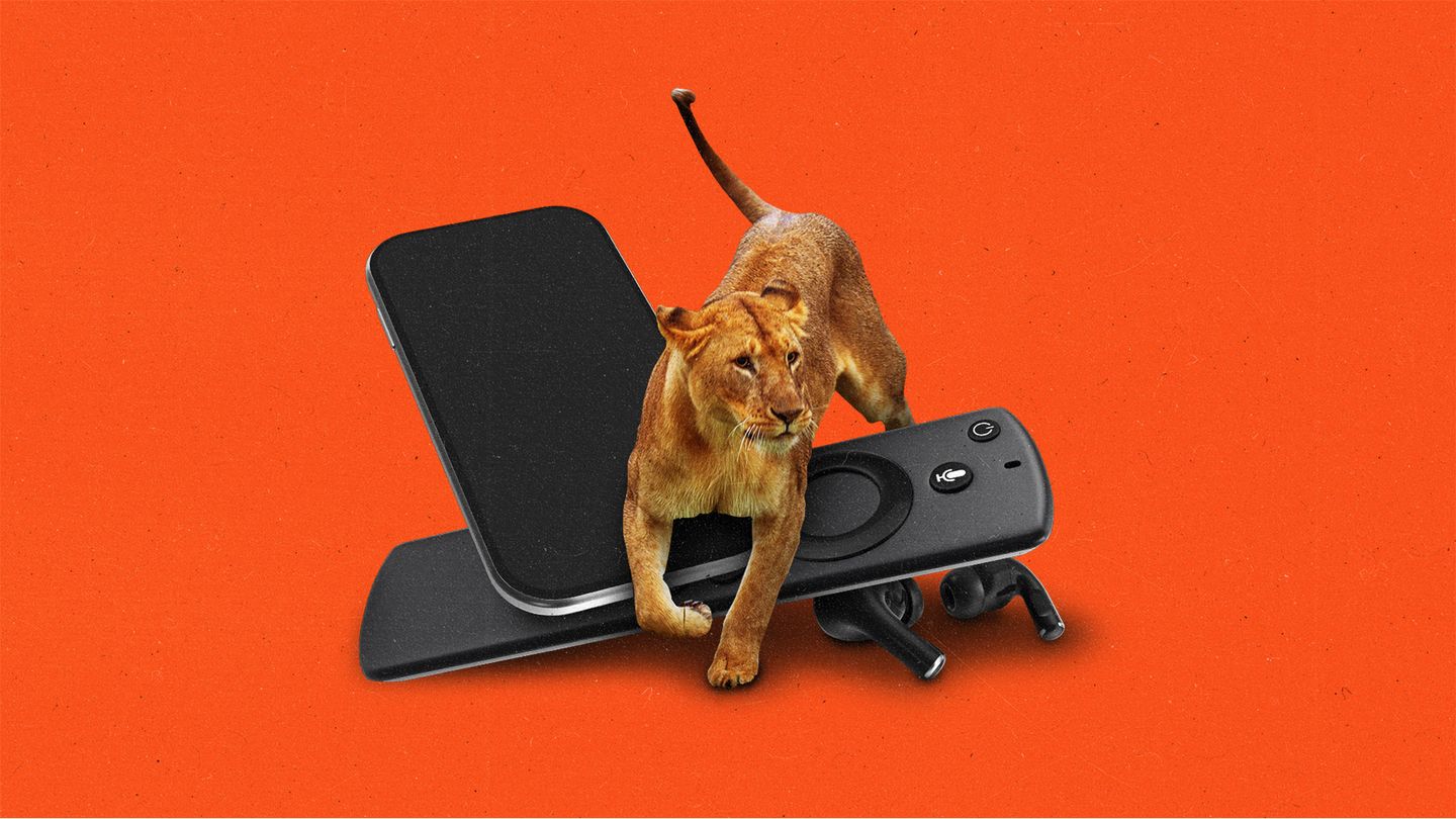 Female lion jumping over a pile of devices, a smartphone, streaming remote, and bluetooth earbuds.