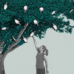 A woman reaches up a picks a finger cursor off of a tree.