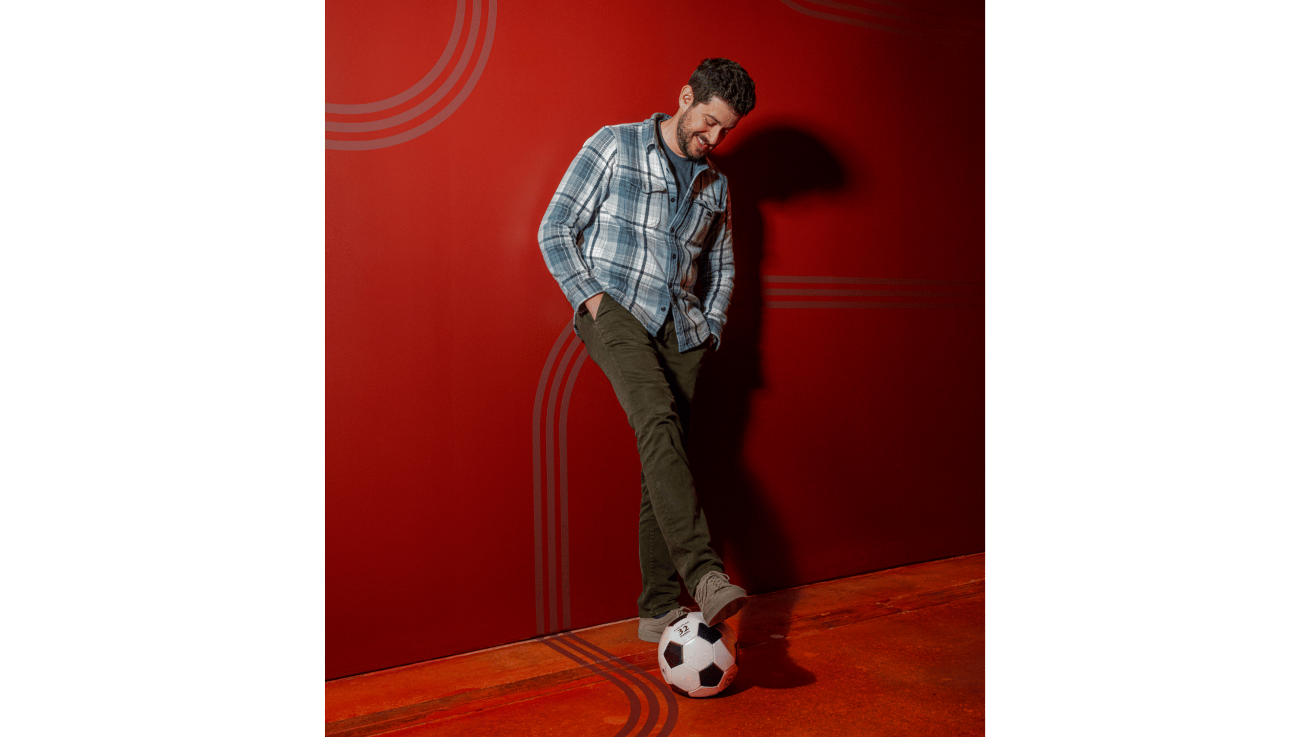 Man posing with soccer ball against red background
