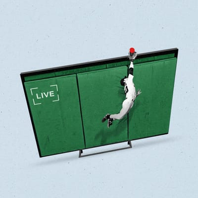 A baseball player jumps to catch a ball over a tv screen that looks like a field.