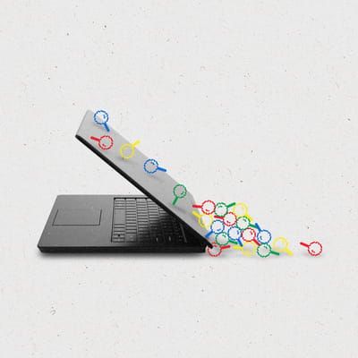 Pixelated magnifying glass icons in red, blue, yellow and green sliding down the back of a laptop, landing in a pile.
