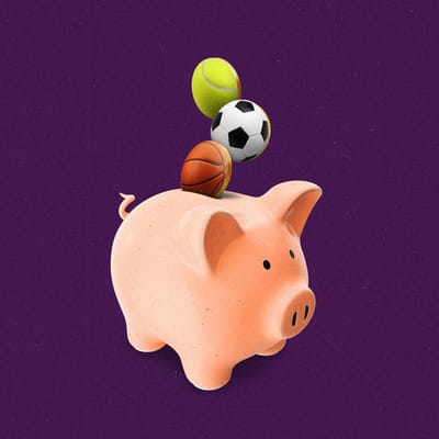 Basketball, soccer ball, and tennis ball on coins all falling into a piggy bank.
