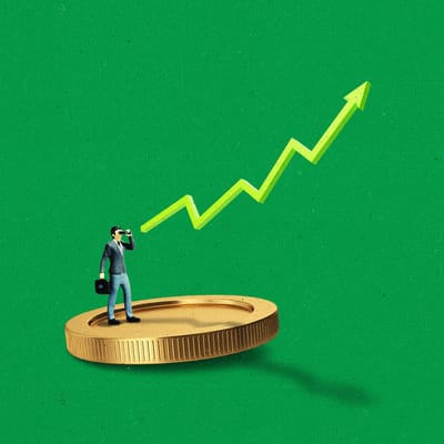 A miniature business person standing on a large coin, pointing towards an upward-trending line.
