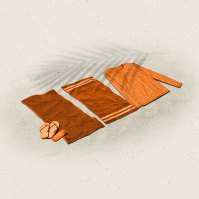 Orange beach towels next to a sweater on sand with a palm tree leaf shadow.