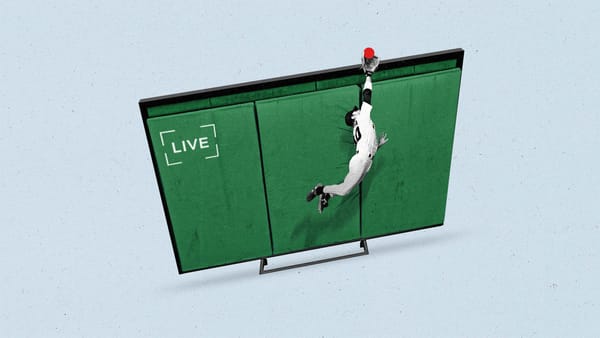 A baseball player jumps to catch a ball over a tv screen that looks like a field.