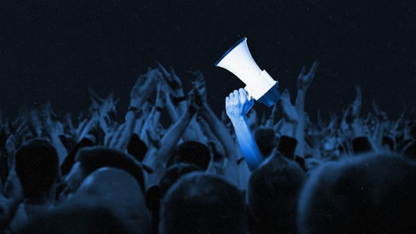 Crowd of fans cheering, with an arm holding up a megaphone amongst them.