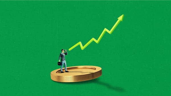 A miniature business person standing on a large coin, pointing towards an upward-trending line.