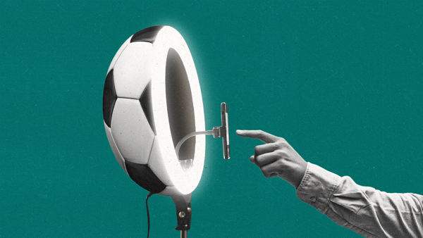 A hand presses a button on a phone sticking out of a ring light shaped like a soccer ball.